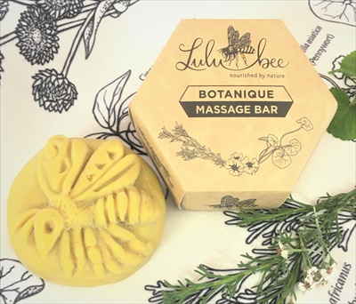 A top image of the Botanique Massage Bar product. the Bee lotion bar on the left and the hexagonal packaging bix on the right. Moisturising massage balm